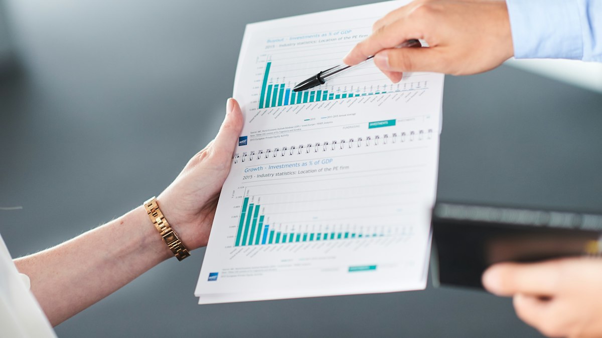 Deux personnes analysent un document financier avec des graphiques en barres vertes